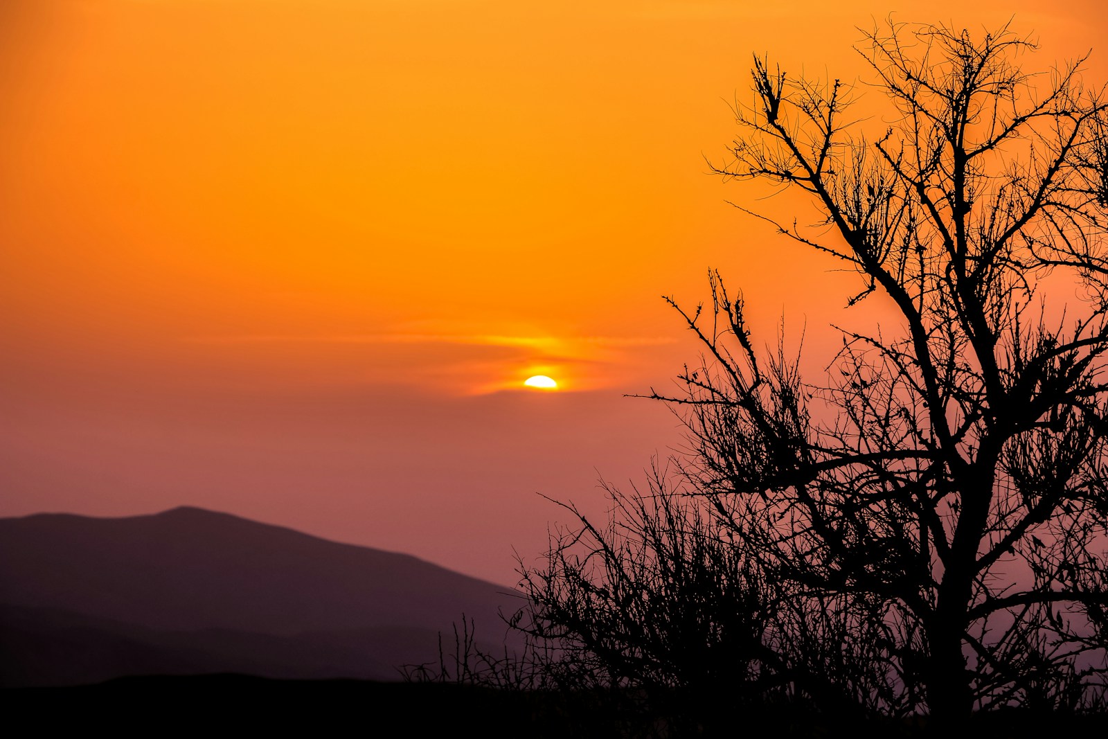 the sun is setting over a mountain range
